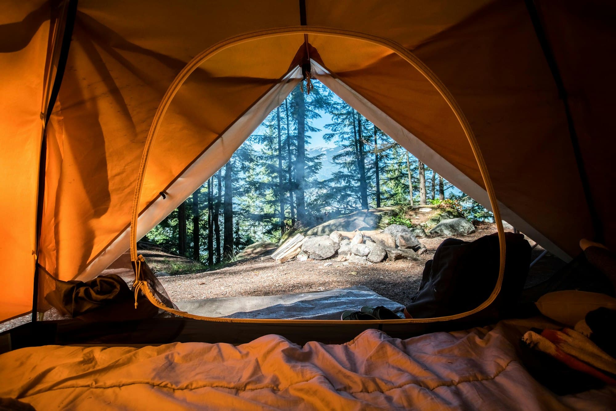 Campsite at dusk with a glowing tent beside a lake