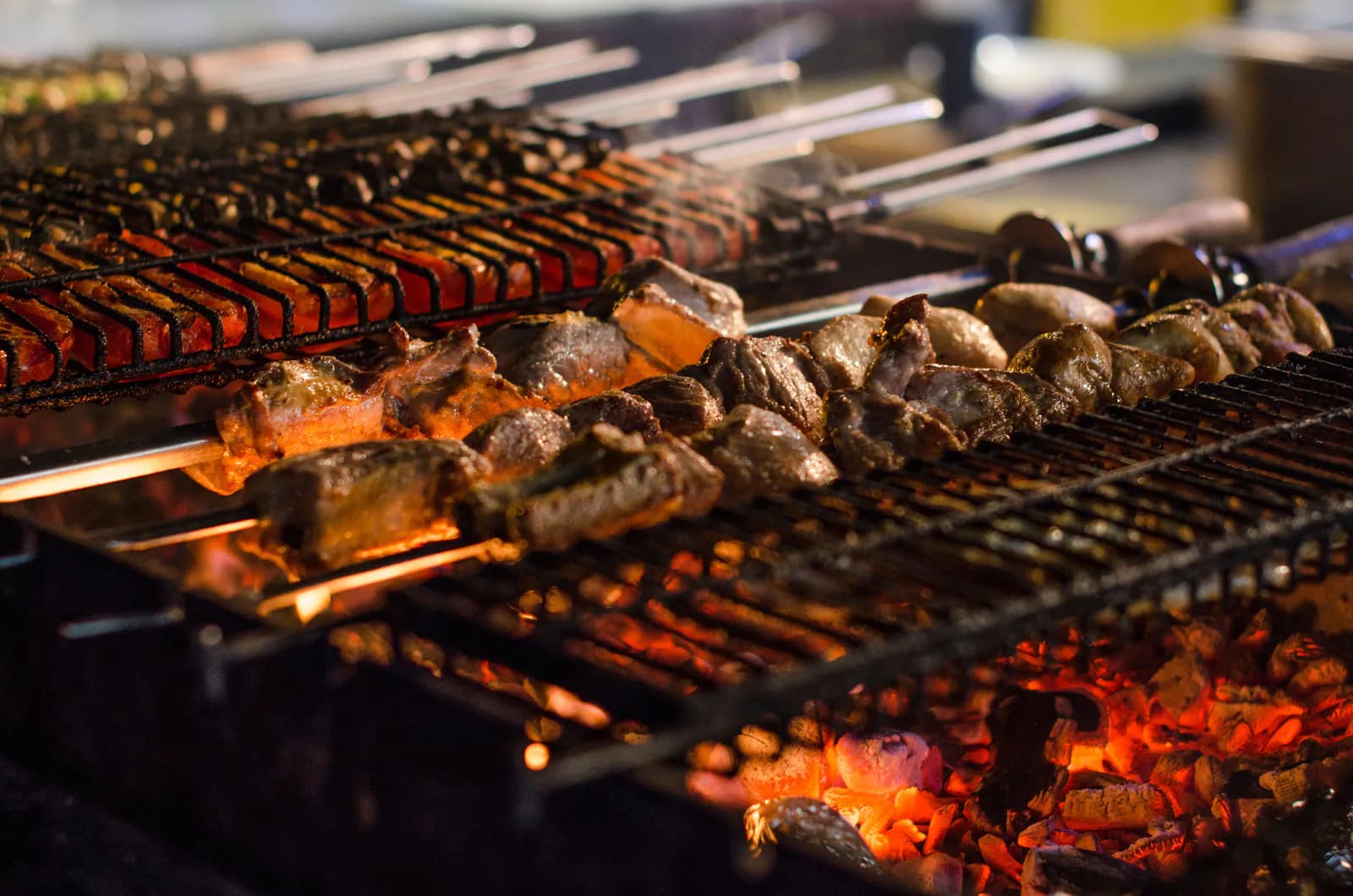 Mixed skewers and grilled meat cooking above glowing charcoal