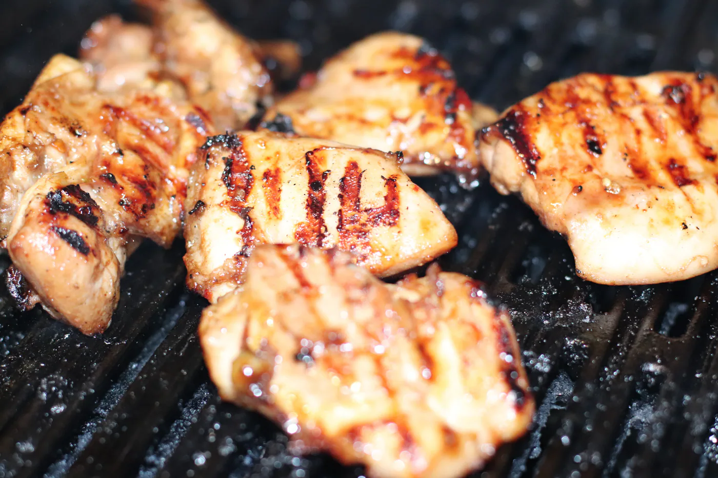 Barbecue chicken pieces browning on a clean grill grate